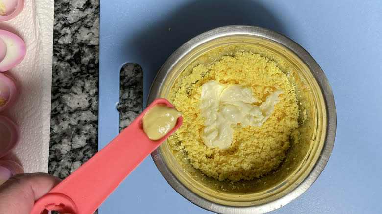 hand adding mustard to yolks