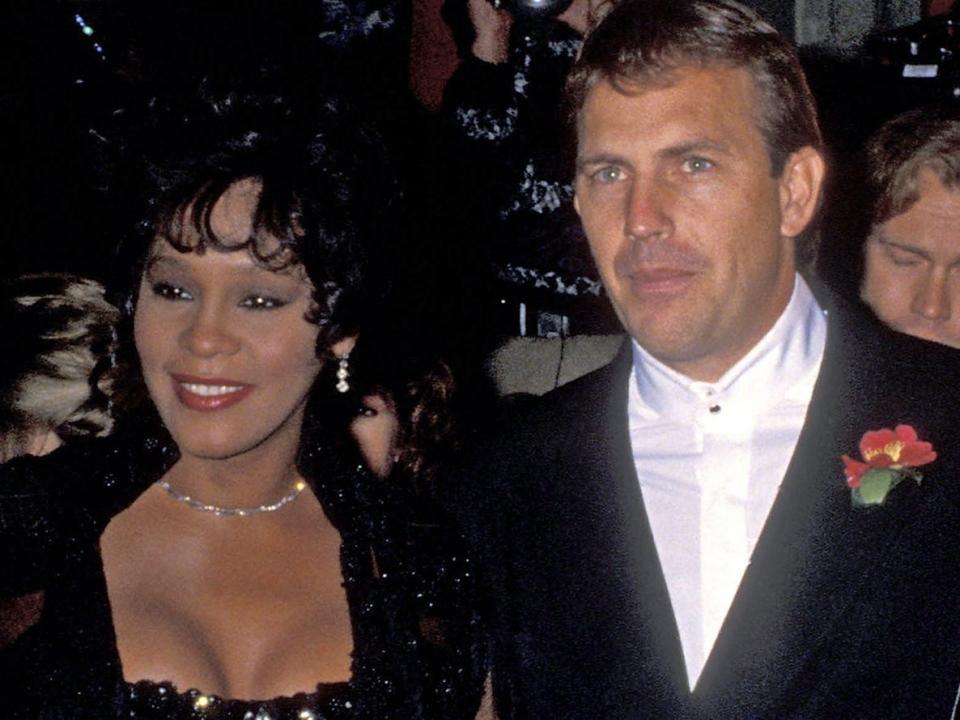 Whitney Houston and Kevin Costner standing next to each other