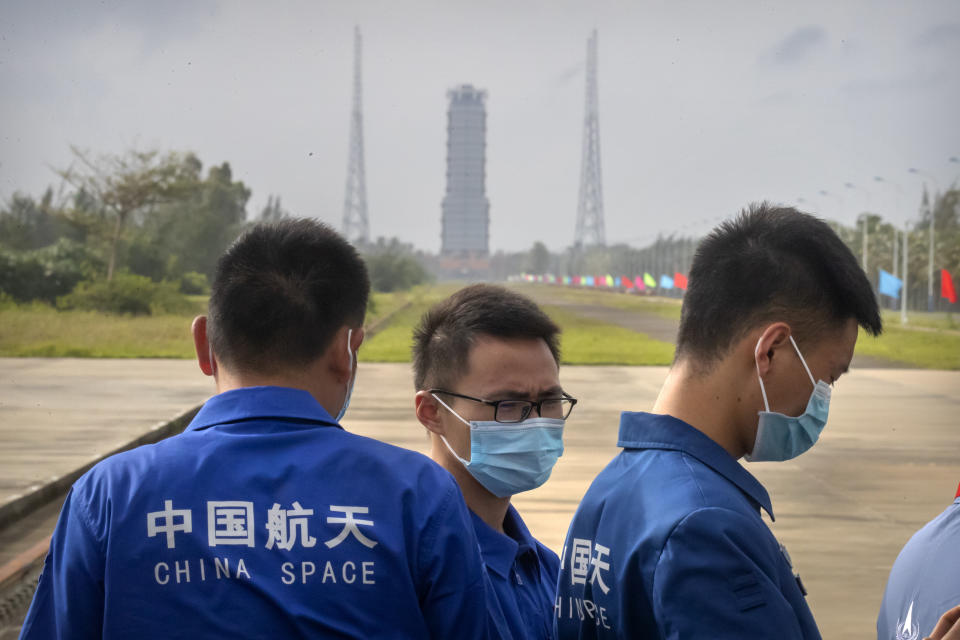 Workers wearing face masks stand near a launch pad at the Wenchang Space Launch Site in Wenchang in southern China's Hainan province, Monday, Nov. 23, 2020. Chinese technicians were making final preparations Monday for a mission to bring back material from the moon's surface for the first time in nearly half a century — an undertaking that could boost human understanding of the moon and of the solar system more generally. (AP Photo/Mark Schiefelbein)