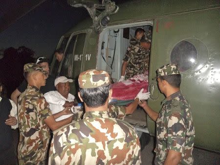 Nepalese army personnel carry a victim rescued from the avalanche inside a helicopter at Thorang-La in Annapurna Region in this October 15, 2014 handout photo provided by Nepal Army. REUTERS/Nepal Army/Handout via Reuters