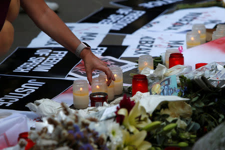 A woman places a candle at an impromptu memorial during a protest by journalists following the assassination of investigative journalist Daphne Caruana Galizia in a car bomb attack three days ago, in Valletta, Malta, October 19, 2017. REUTERS/Darrin Zammit Lupi