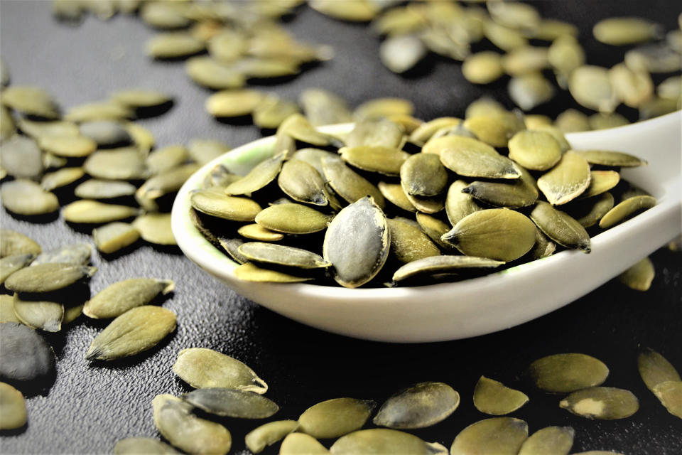 Pumpkin seeds in a bowl and on a table.