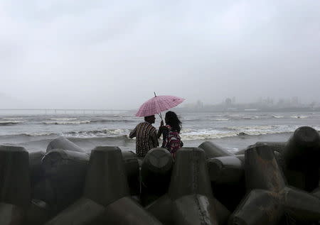 A couple takes cover from rain under an umbrella along the shores of the Arabian Sea in Mumbai, June 23, 2015. REUTERS/Shailesh Andrade