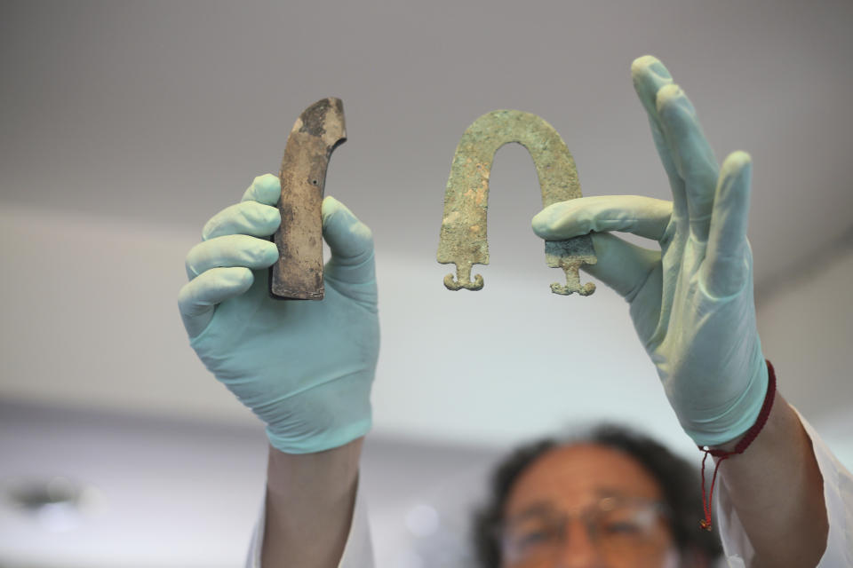 Jedu Sadarnaga shows jewelry on Thursday, Nov. 15, 2018 from one of the tombs found at a Bolivian quarry near the capital of La Paz. The tombs contained remains belonging to more than 100 individuals and were buried with more than 30 vessels used by the Incas. (AP Photo/Luis Gandarillas)