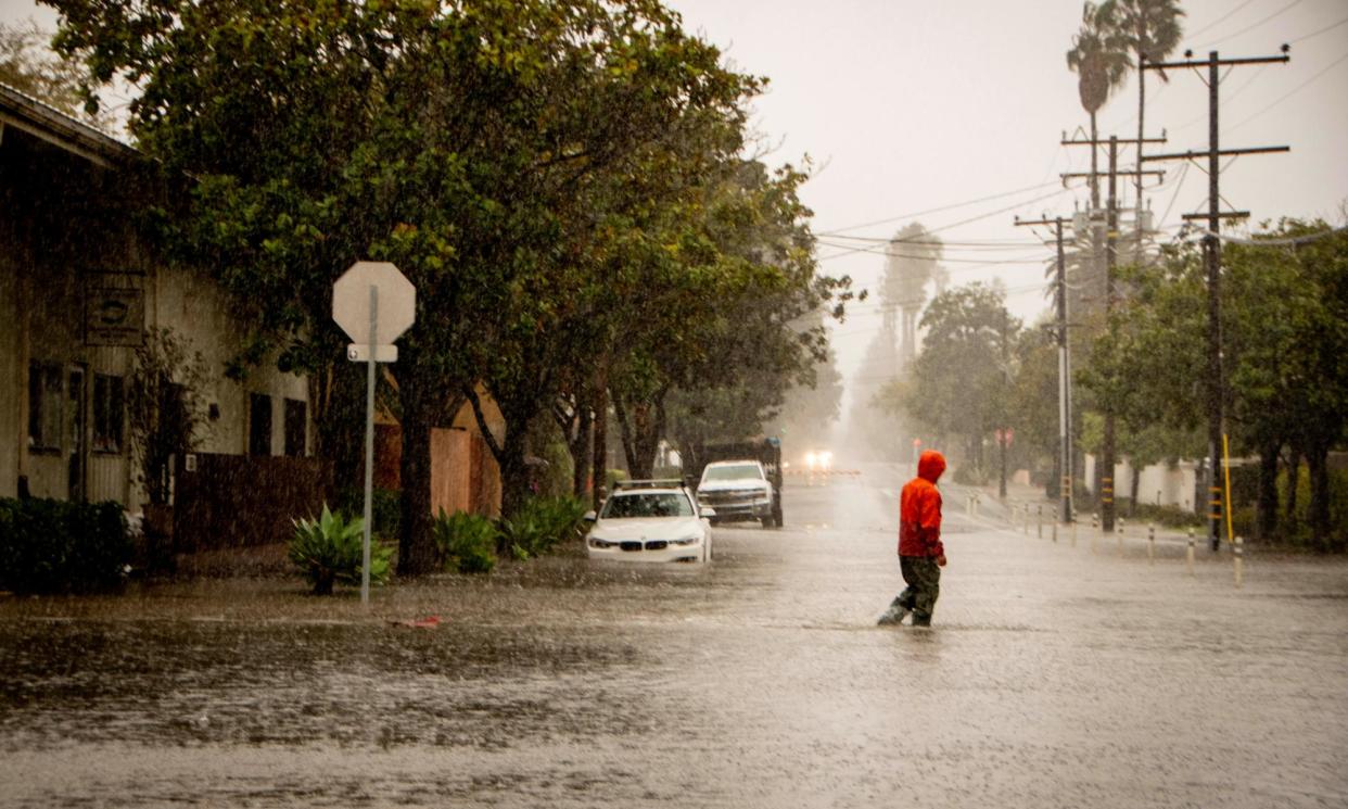 <span>A man crosses a flooded street in Santa Barbara, California, on 4 February 2024. </span><span>Photograph: Erick Madrid/EPA</span>