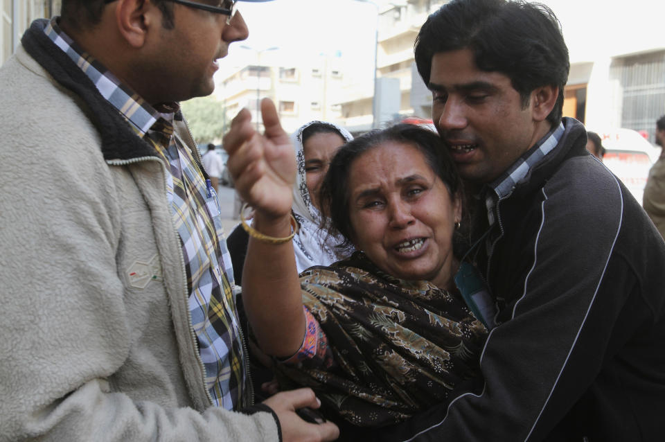 People comfort a woman who said she lost her husband in an attack on Wednesday, Jan. 29, 2014, in Karachi, Pakistan. Police said several members of the country's security forces have been killed in separate attacks in the southern city of Karachi. (AP Photo/Fareed Khan)