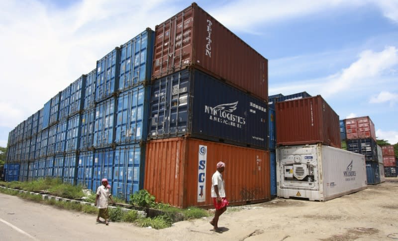 Workers walk past containers at a depot on Willingdon Island