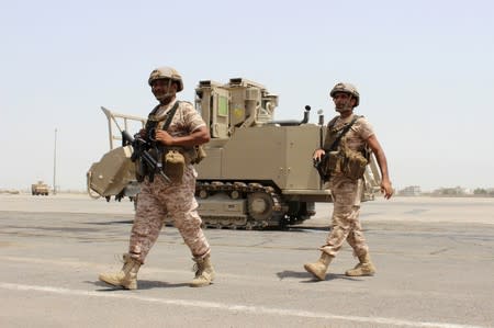 Soldiers from the United Arab Emirates walk past a military vehicle at the airport of Yemen's southern port city of Aden