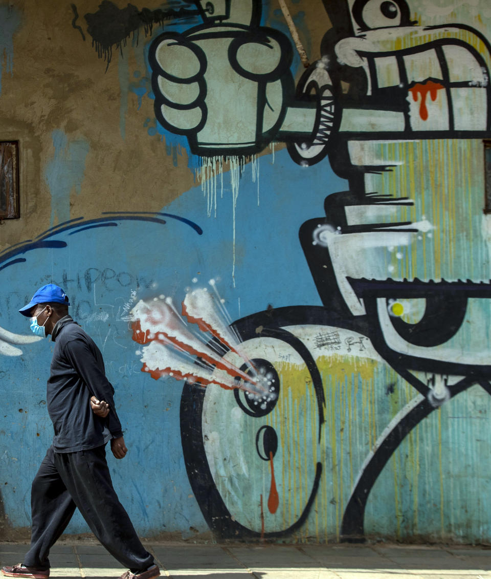 A man wearing face masks to protect against coronavirus, walks past a mural on the street in downtown Johannesburg, South Africa, Thursday, April 9, 2020. South Africa and more than half of Africa's 54 countries have imposed lockdowns, curfews, travel bans or other restrictions to try to contain the spread of COVID-19. The new coronavirus causes mild or moderate symptoms for most people, but for some, especially older adults and people with existing health problems, it can cause more severe illness or death. (AP Photo/Themba Hadebe)