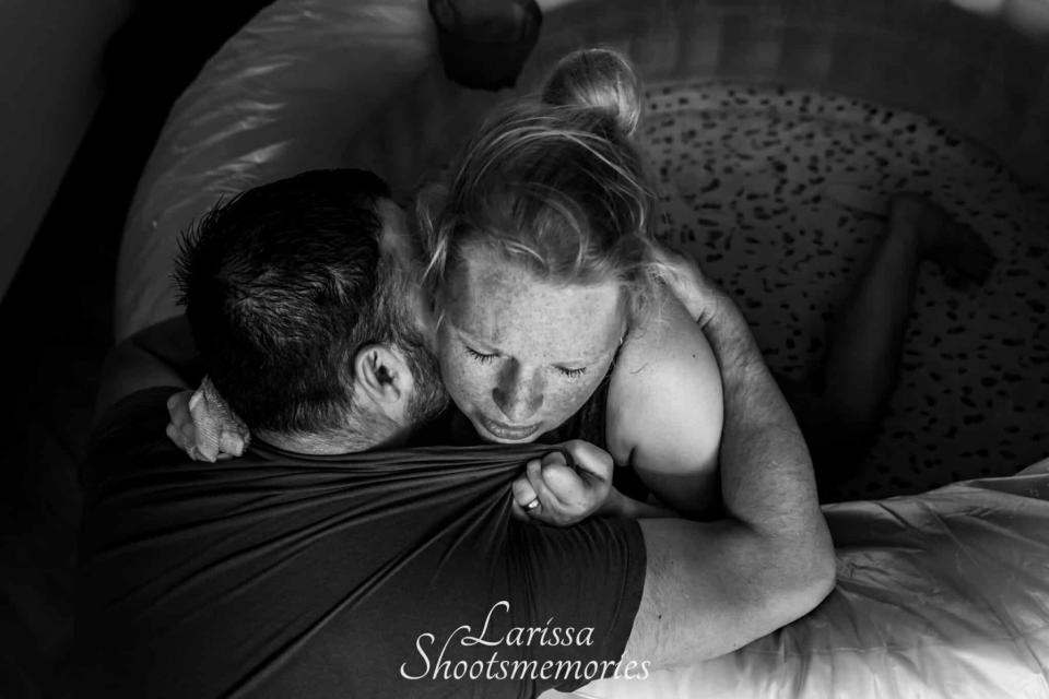 Woman in labor supported by partner in a birthing pool, showing a moment of comfort and care