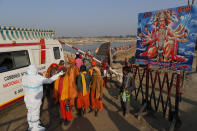 A health worker takes nasal swab samples of Hindu holy men, to test for COVID-19 next to a poster of Hindu God Hanuman during Magh Mela festival, in Prayagraj, India. Wednesday, Feb. 24, 2021. Millions of people have joined a 45-day long Hindu bathing festival in this northern Indian city, where devotees take a holy dip at Sangam, the sacred confluence of the rivers Ganga, Yamuna and the mythical Saraswati. Here, they bathe on certain days considered to be auspicious in the belief that they be cleansed of all sins. (AP Photo/Rajesh Kumar Singh)