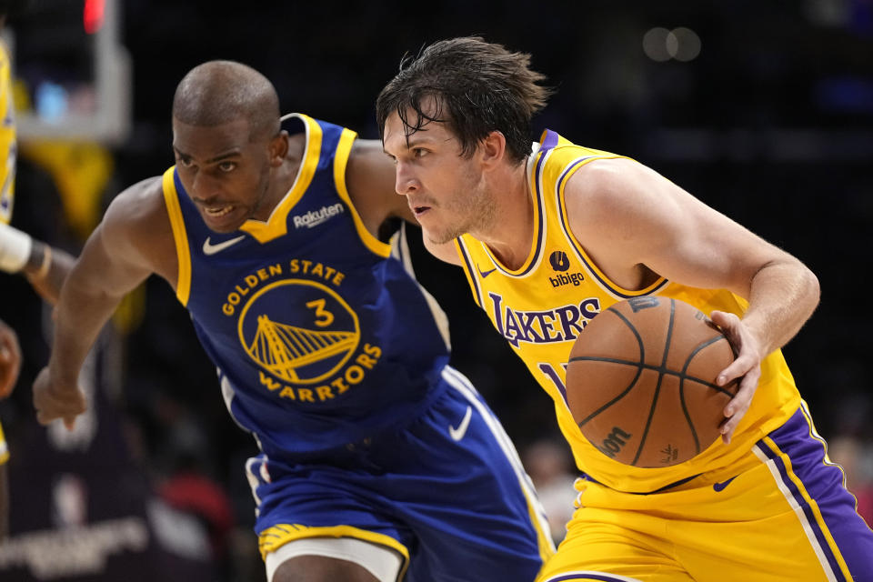 Los Angeles Lakers guard Austin Reaves, right, drives by Golden State Warriors guard Chris Paul during the first half of an NBA preseason basketball game Friday, Oct. 13, 2023, in Los Angeles. (AP Photo/Mark J. Terrill)