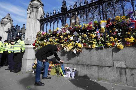 A man looks at floral tributes resting against a wall surrounding the House of Parliament, following the attack in Westminster earlier in the week, in London, Britain March 25, 2017. REUTERS/Peter Nicholls