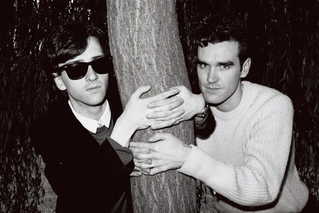 Johnny Marr (left) and Morrissey of the group The Smiths posed with their arms around a tree trunk in London in 1983. - Credit: Clare Muller/Redferns/Getty Images