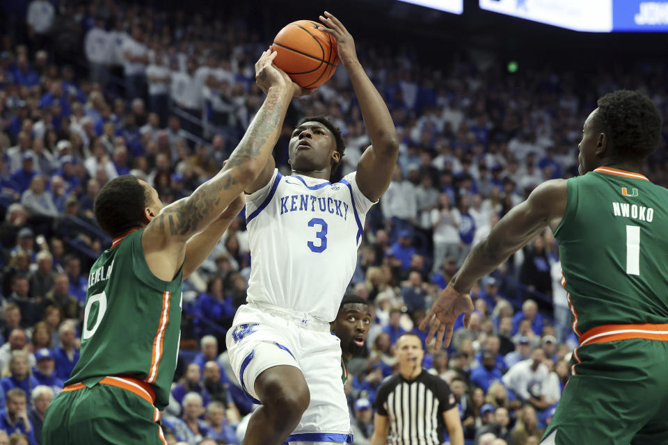 Kentucky's Adou Thiero (3) shoots near Miami's Matthew Cleveland (0) and Michael Nwoko (1) during the first half of an NCAA college basketball game in Lexington, Ky., Tuesday, Nov. 28, 2023. (AP Photo/James Crisp)