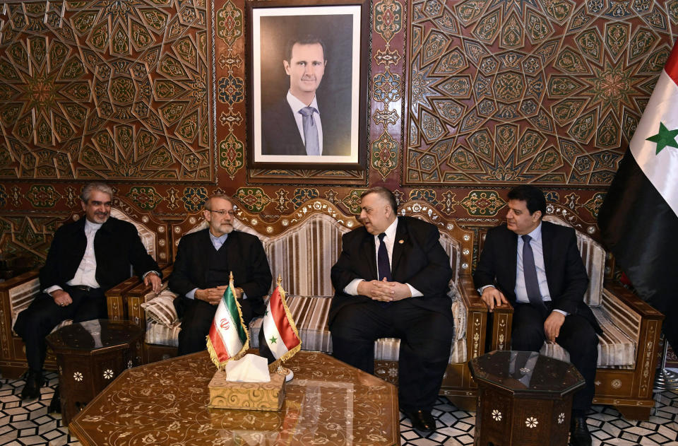 In this photo released by the Syrian official news agency SANA, Speaker of the People's Council of Syria Hammouda Sabbagh, center right, receives Iran's Parliament Speaker Ali Larijani, second left, on his arrival to the airport, in the Syrian capital Damascus, Sunday, Feb. 16, 2020. (SANA via AP)