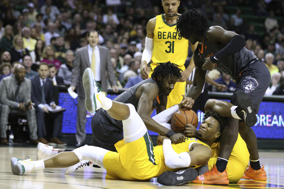 Baylor forward Freddie Gillespie, center, grabs a rebound between Oklahoma State forward Kalib Boone, left, and guard Isaac Likekele, right, during the first half of an NCAA college basketball game Saturday, Feb. 8, 2020, in Waco, Texas. (AP Photo/Rod Aydelotte)