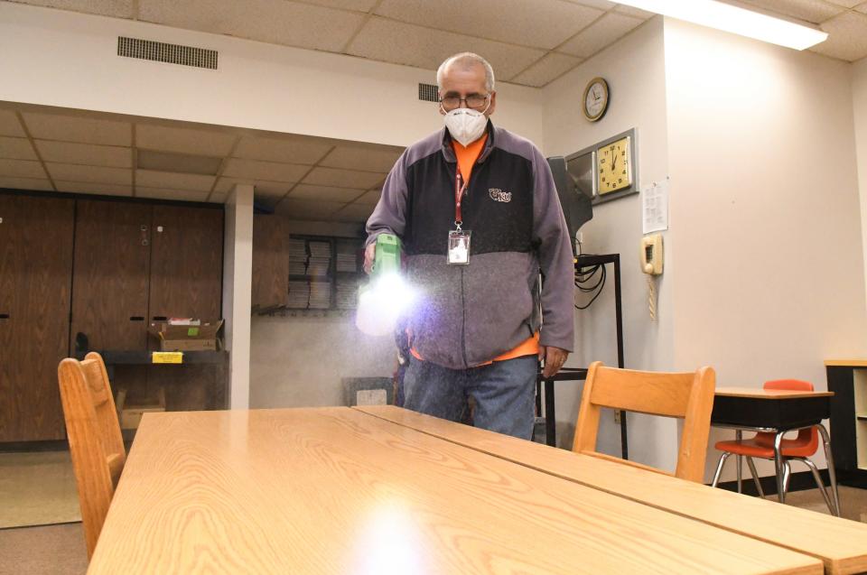 Custodian Rick Wilson cleans a desk using an electrostatic sprayer at John S. Clarke Elementary School in Pottsville, Pa.