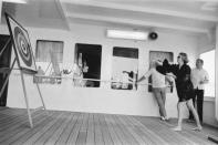 <p>The Princess of Monaco enjoys a leisurely day on a boat and plays a game of darts on the aft deck, while dressed in a casual black long-sleeve cover-up.</p>