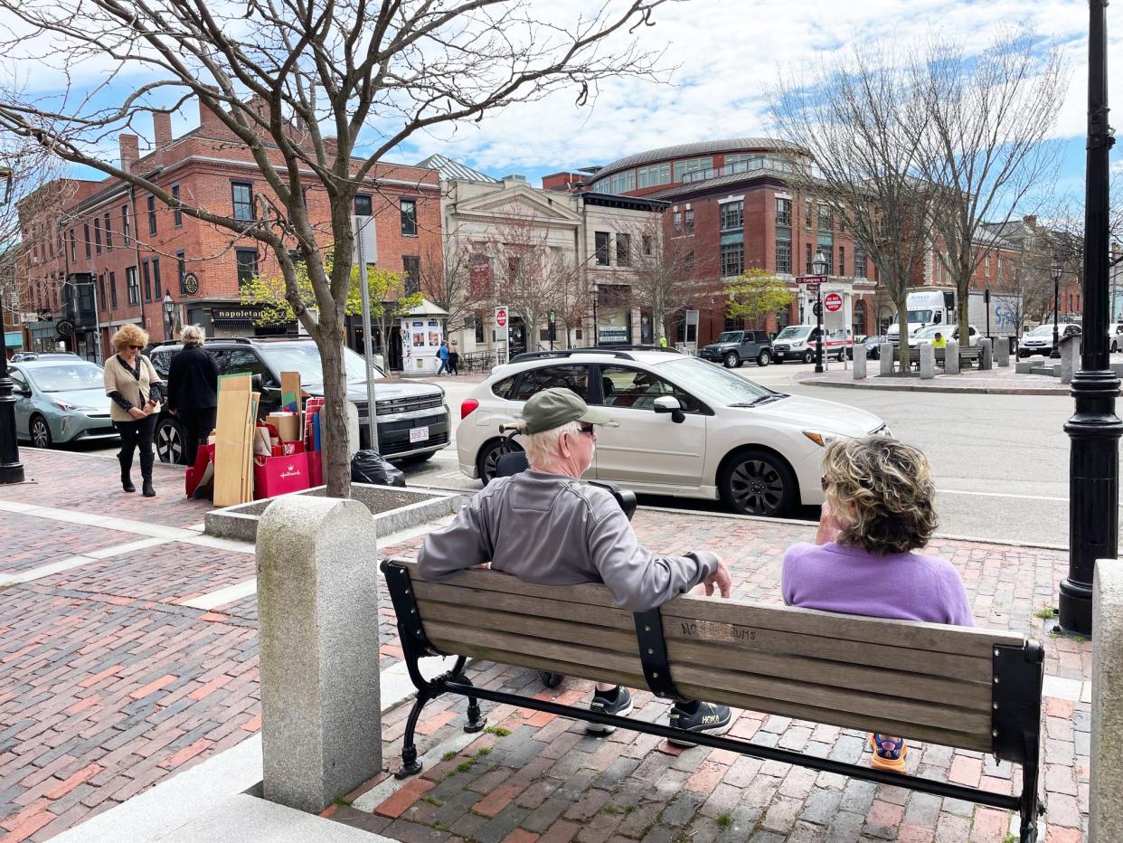 People sit on a bench in Market Square as cars park in 15 minute spaces April 29, 2024.