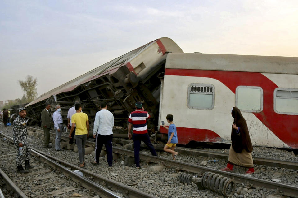 People gather at the site where a passenger train derailed injuring at least 100 people, near Banha, Qalyubia province, Egypt, Sunday, April 18, 2021. At least eight train wagons ran off the railway, the provincial governor's office said in a statement. (AP Photo/Fadel Dawood)