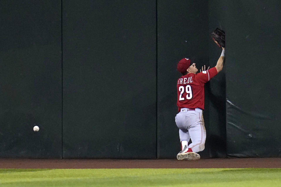 Cincinnati Reds center fielder TJ Friedl crashes into the center field wall on a triple hit by Arizona Diamondbacks' Corbin Carroll during the fifth inning of a baseball game Sunday, Aug. 27, 2023, in Phoenix. Diamondbacks' Carroll was thrown out at home plate trying to stretch the triple into and inside-the-park home run. (AP Photo/Ross D. Franklin)