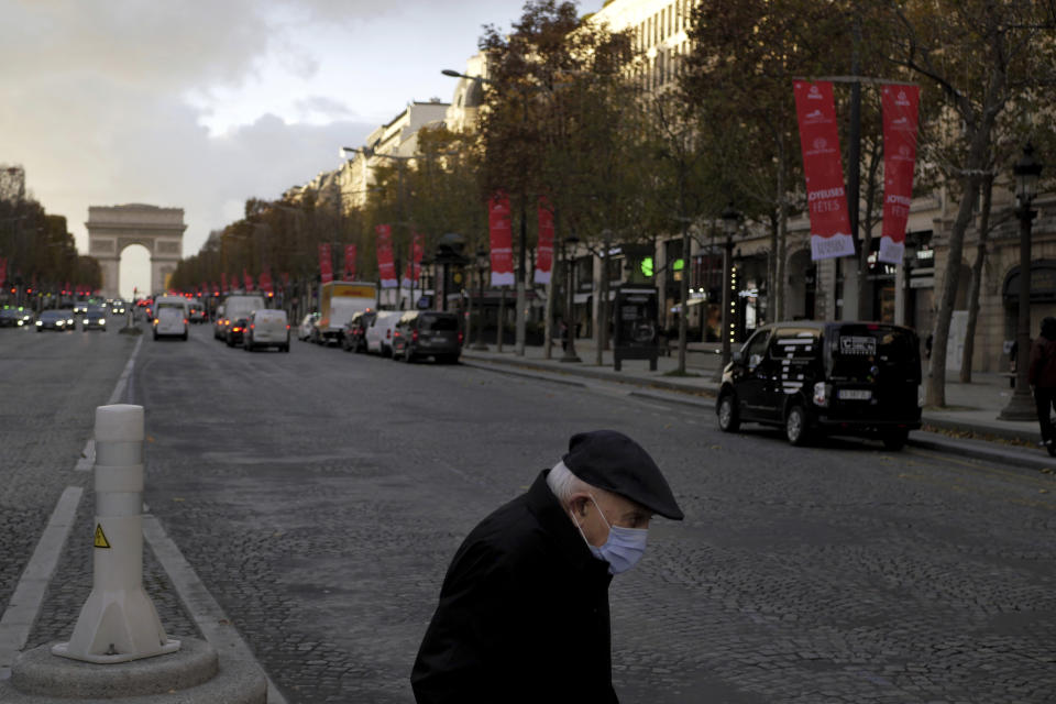 An elderly man wears a face mask as he walks on the Champs Elysee avenue, in Paris, Thursday, Nov. 19, 2020. France has surpassed 2 million confirmed cases of coronavirus, the fourth-highest total in the world. (AP Photo/Thibault Camus)