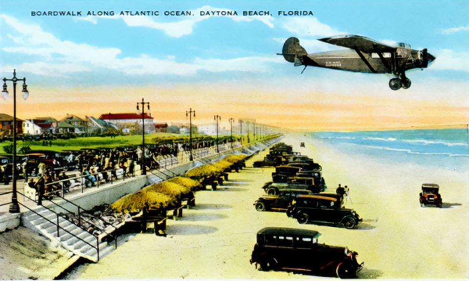 A monoplane flying past the pre-Bandshell Boardwalk in Daytona Beach in a postcard photo.