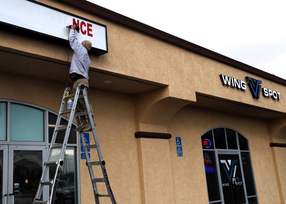 A worker takes down an appliance store sign in January 2024 to make way for an expansion of the Wing Spot restaurant on Lake Boulevard.