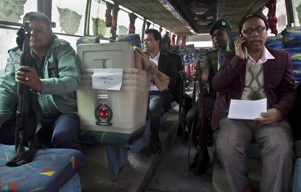 Bangladeshi polling officials accompanied by police personnel wait inside a bus before leaving for a polling station on the eve of the general elections in Dhaka, Bangladesh, Saturday, Dec. 29, 2018. As Bangladeshis get set for Sunday's parliamentary elections, there are fears that violence and intimidation could keep many away from the polls, including two opposition candidates who said police had barricaded them inside their homes. (AP Photo/Anupam Nath)