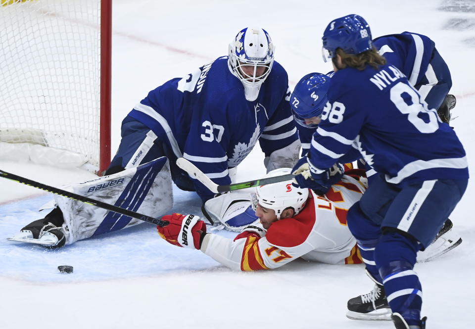 Toronto Maple Leafs goaltender Michael Hutchinson (30) makes a save against Calgary Flames left wing Milan Lucic (17) as Maple Leafs center Travis Boyd (72) gets a penalty on the play while Maple Leafs right wing William Nylander (88) looks on during the second period of an NHL hockey game in Toronto on Monday, Feb. 22, 2021. (Nathan Denette/The Canadian Press via AP)