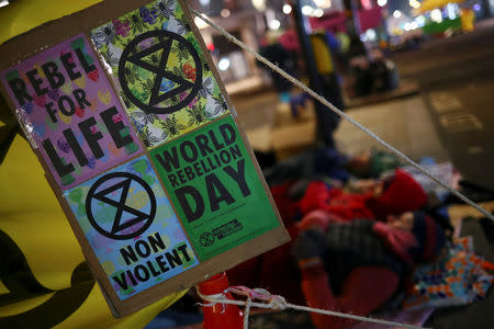 Signs are seen near climate change activists resting during a Extinction Rebellion protest at Oxford Circus in London, Britain April 16, 2019. REUTERS/Hannah McKay