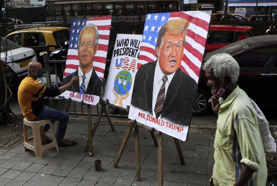 Indian art teacher Sagar Kambli makes paintings of President Donald Trump and Democratic rival Joe Biden on a pavement outside his art school remaining closed due to the COVID-19 pandemic in Mumbai, India, Thursday, Oct. 29, 2020. (AP Photo/Rajanish Kakade)