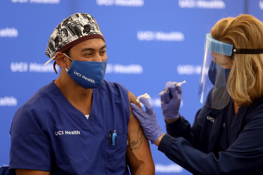 ORANGE, CA - DECEMBER 16: Erik Mara, a respiratory therapist at UCI Health, receives a Pfizer BioNTech COVID-19 vaccine administered by UCI Health Registered Nurse Pam Samuelson, to its highest-risk frontline clinicians at the University of California, Irvine Medical Center on Wednesday, Dec. 16, 2020 in Orange, CA. (Gary Coronado / Los Angeles Times)