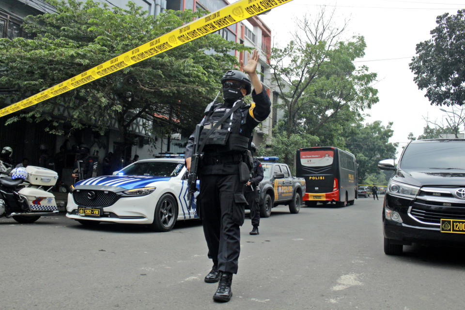 A police officer gestures at the crowd to move back as he guards a road leading to a police station where a bomb exploded in Bandung, West Java, Indonesia, Wednesday, Dec. 7, 2022. A man blew himself up Wednesday at a police station on Indonesia's main island of Java in what appeared to be the latest in a string of suicide attacks in the world's most populous Muslim nation. (AP Photo/Kholid Parmawinata)