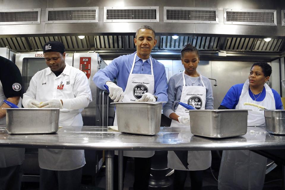 U.S. President Barack Obama (C) smiles as he and his daughter Sasha (2nd R) fill burritos as they volunteer at the DC Central Kitchen charity in honor of the Martin Luther King Jr. holiday, in Washington, January 20, 2014. REUTERS/Jonathan Ernst (UNITED STATES - Tags: POLITICS ANNIVERSARY)