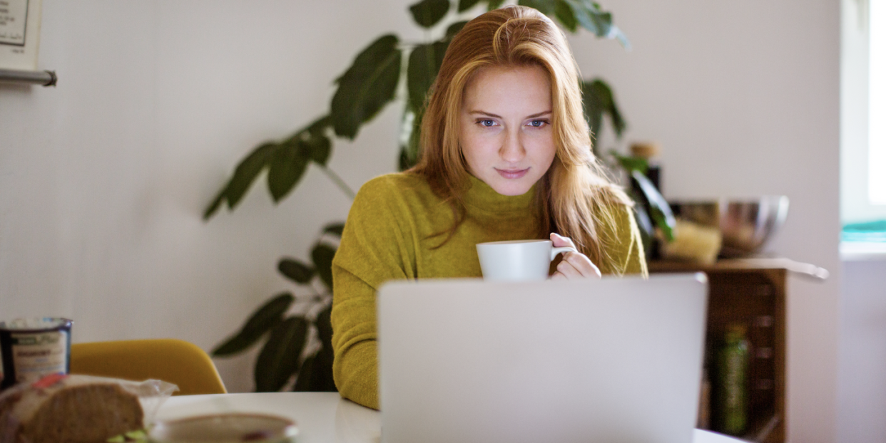 a woman works from home on her laptop drinking tea