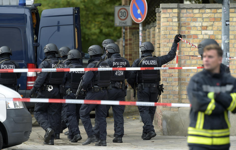 Police officers walk in front of a Jewish cemetery in Halle, Germany, Wednesday, Oct. 9, 2019. One or more gunmen fired several shots on Wednesday in the German city of Halle. Police say a person has been arrested after a shooting that left two people dead. (AP Photo Jens Meyer)