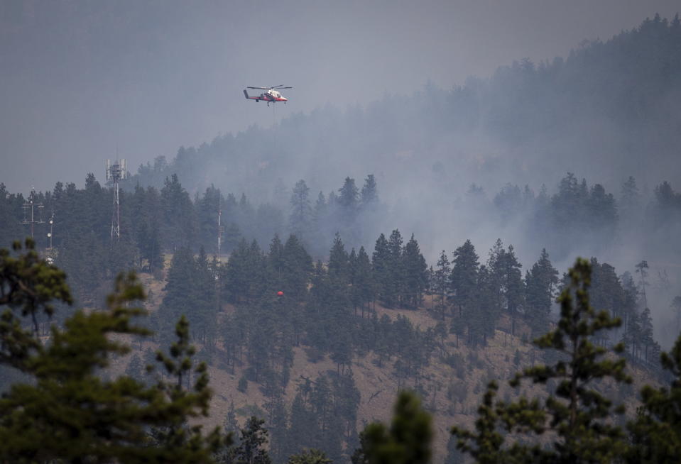 A helicopter pilot prepares to drop water on a wildfire burning in Lytton, British Columbia, on Friday, July 2, 2021. (Darryl Dyck/The Canadian Press via AP)