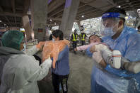 A public health worker helps chinese tourists, who arrived at Suvarnabhumi airport on special tourist visas, in Bangkok, Thailand, Tuesday, Oct. 20, 2020. Thailand on Tuesday took a modest step toward reviving its coronavirus-battered tourist industry by welcoming 39 visitors who flew in from Shanghai, the first such arrival since normal traveler arrivals were banned almost seven months ago. (AP Photo/Wason Wanichakorn)