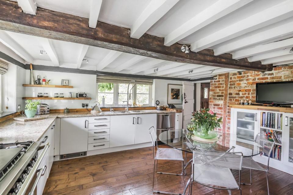 <p>We love this traditional kitchen, which has white cabinets, wooden flooring and gorgeous exposed beams. </p>