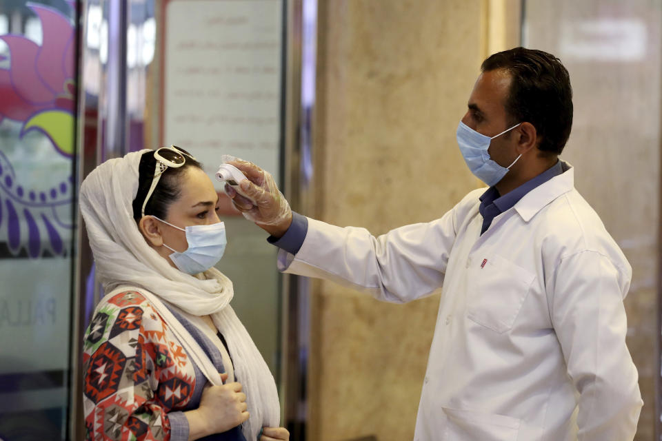 FILE - In this Aug. 19, 2020, file photo, a woman wearing a protective face mask to help prevent spread of the coronavirus has her temperature checked as she enters a shopping center, in Tehran, Iran. As coronavirus infections reached new heights in Iran, overwhelming its hospitals and driving up its death toll, the country’s health minister gave a rare speech criticizing his own government’s refusal to enforce basic health measures. (AP Photo/Ebrahim Noroozi, File)