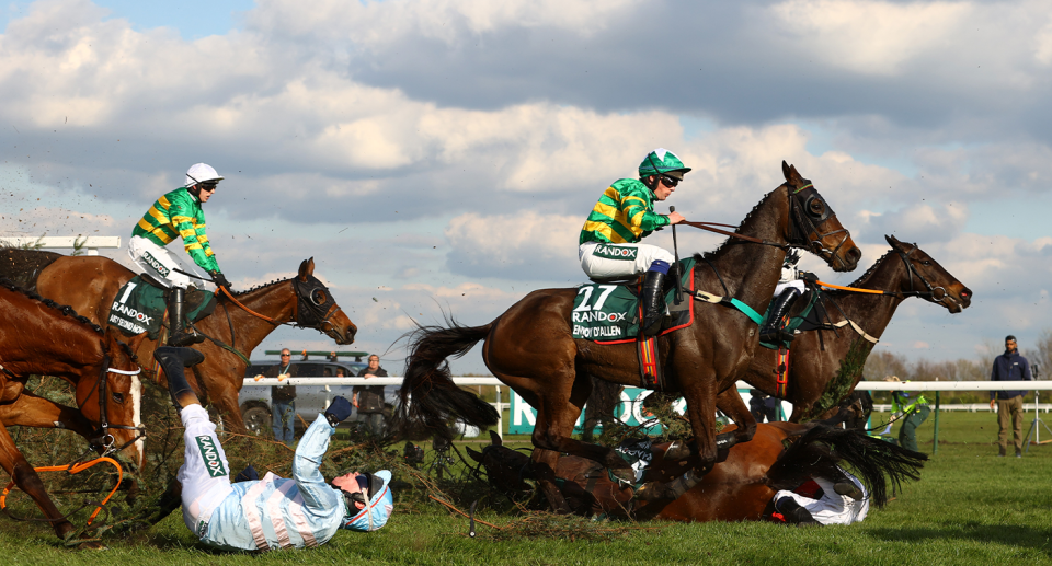 Jockeys fall off their horses at The Grand National race.