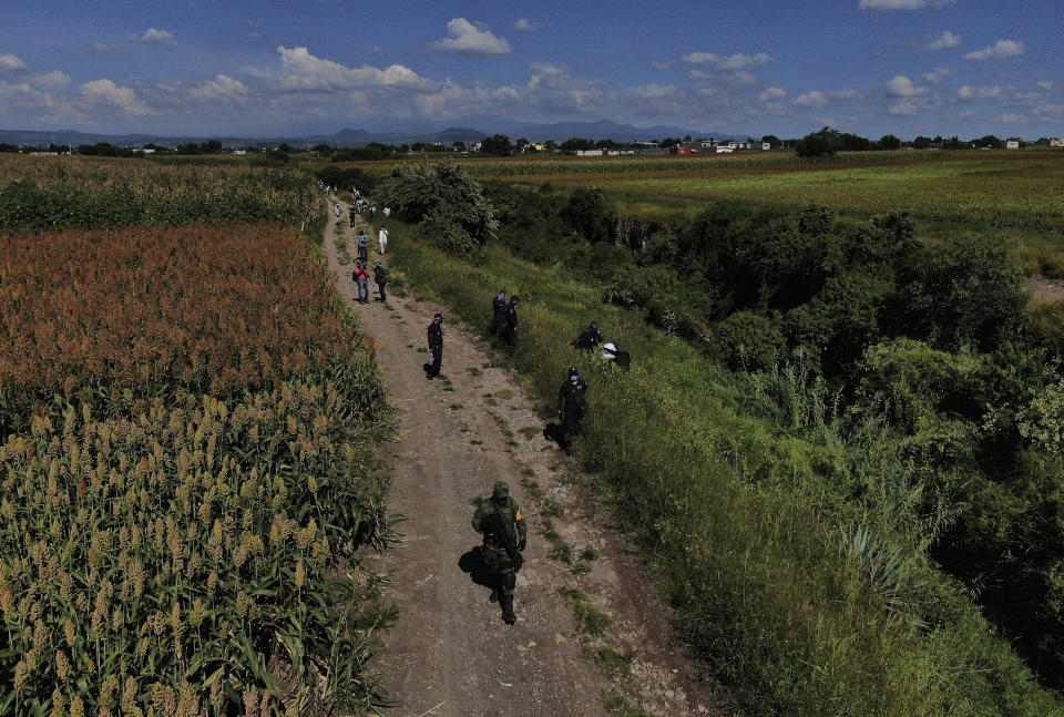 Soldiers and police inspect an area were bodies are suspected of being buried on the outskirts of Cuautla, Mexico, Tuesday, Oct. 12, 2021. The government's registry of Mexico’s missing has grown more than 20% in the past year and now approaches 100,000. (AP Photo/Fernando Llano)