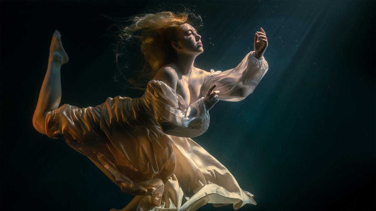  A portrait of a model in a glass tank, creating the illusion of an underwater image . 