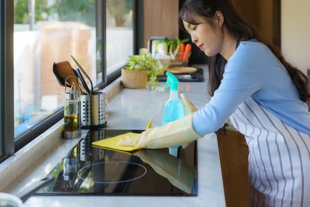 Asian woman housewife rubbing the electric stove with a cloth in the kitchen at home.