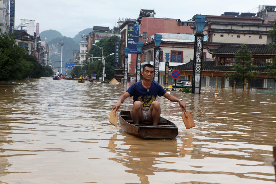 A man paddles through a flooded area