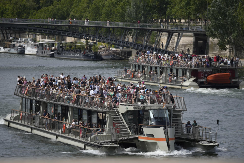 Tourists crowd on river boats on the Seine river, in Paris Thursday, July 20, 2023. The city's tourism office predicts that up to 15.9 million people could visit the Paris region during the July-September period that includes the Olympics and Paralympic Games. (AP Photo/Christophe Ena)