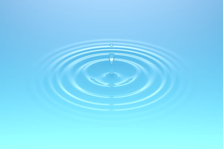 Droplets of water falling into a body of water and creating ripples. Soft light blue-green color.
