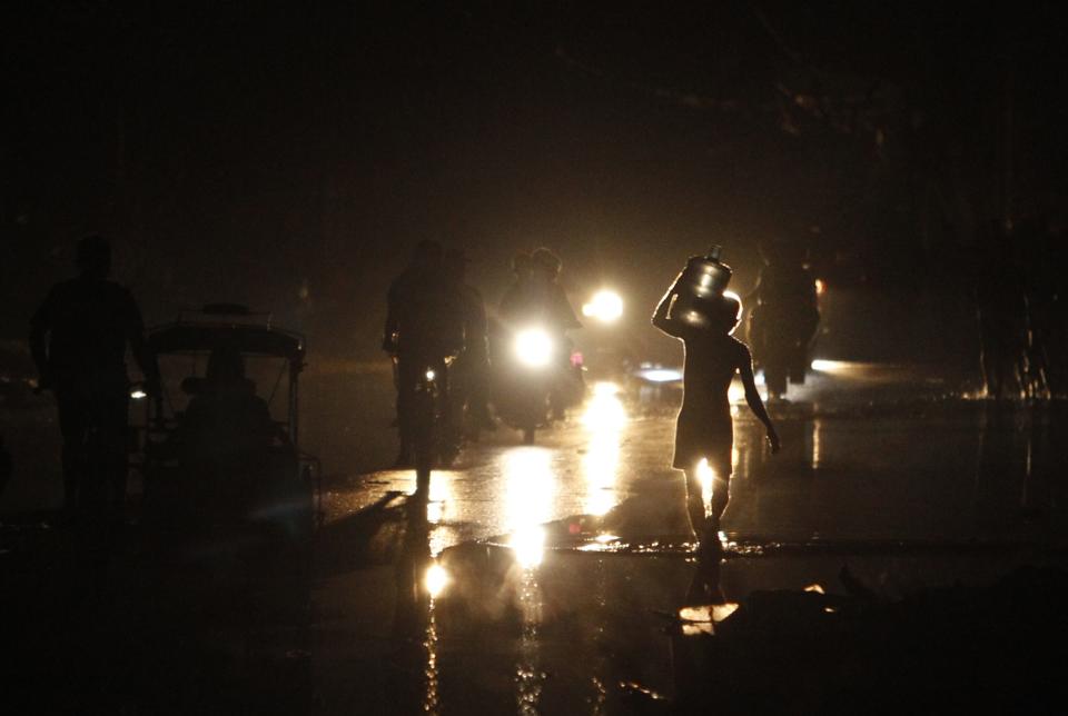 A man carries water as he walks on a flooded street during nightfall after the Super typhoon Haiyan battered Tacloban city in central Philippines